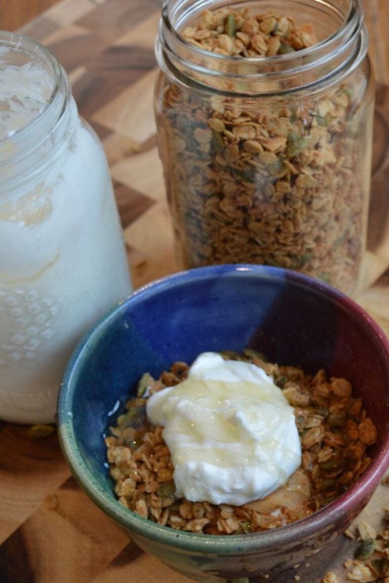 Yogurt in a jar and granola in a jar beside a bowl with yogurt and granola