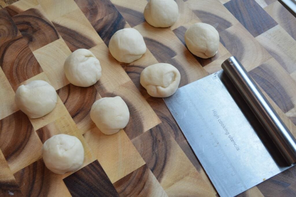 Dough rolled into balls beside bench scraper