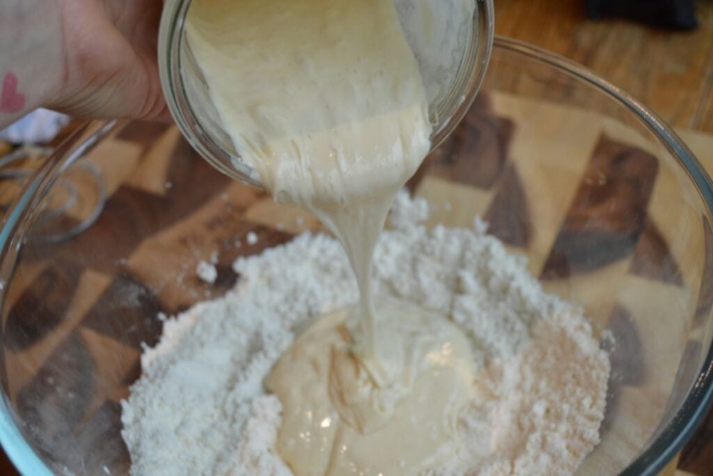 Sourdough discard being poured into bowl of flour