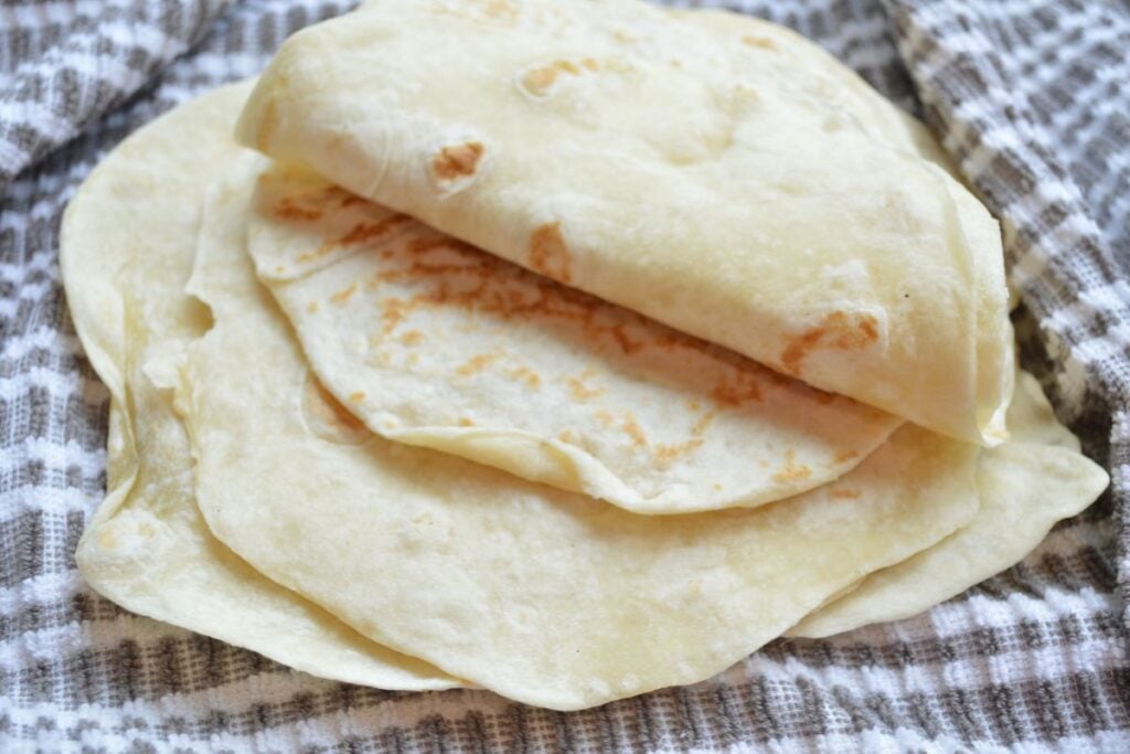 Sourdough tortillas, one folded up in tea towel