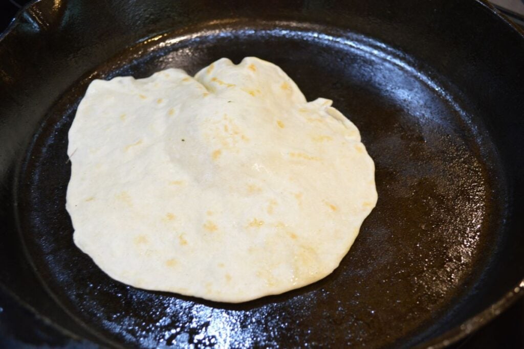 Sourdough tortilla cooking in cast iron pan