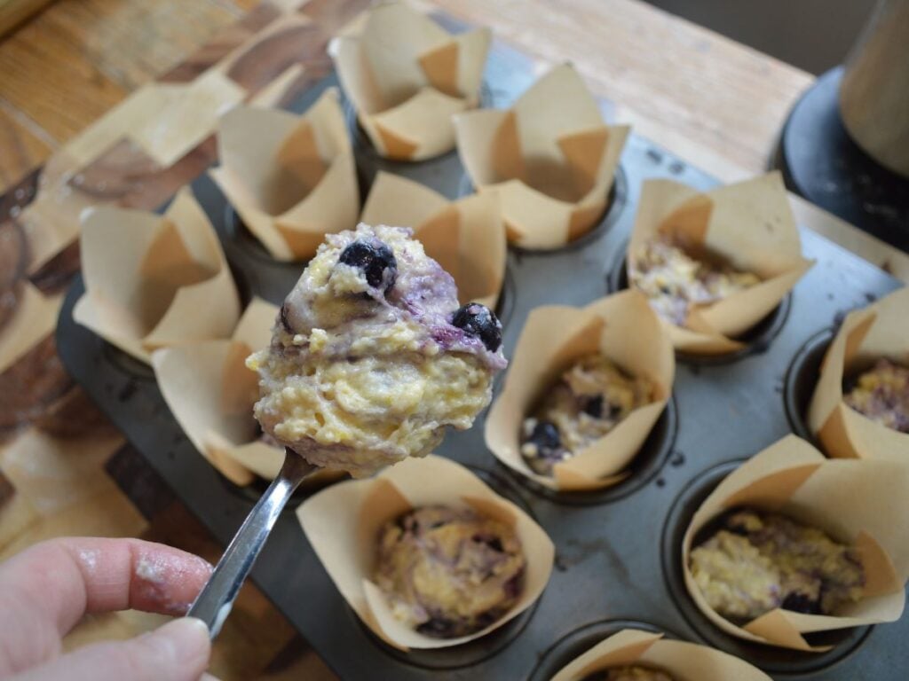 Hand holding spoon of muffin batter