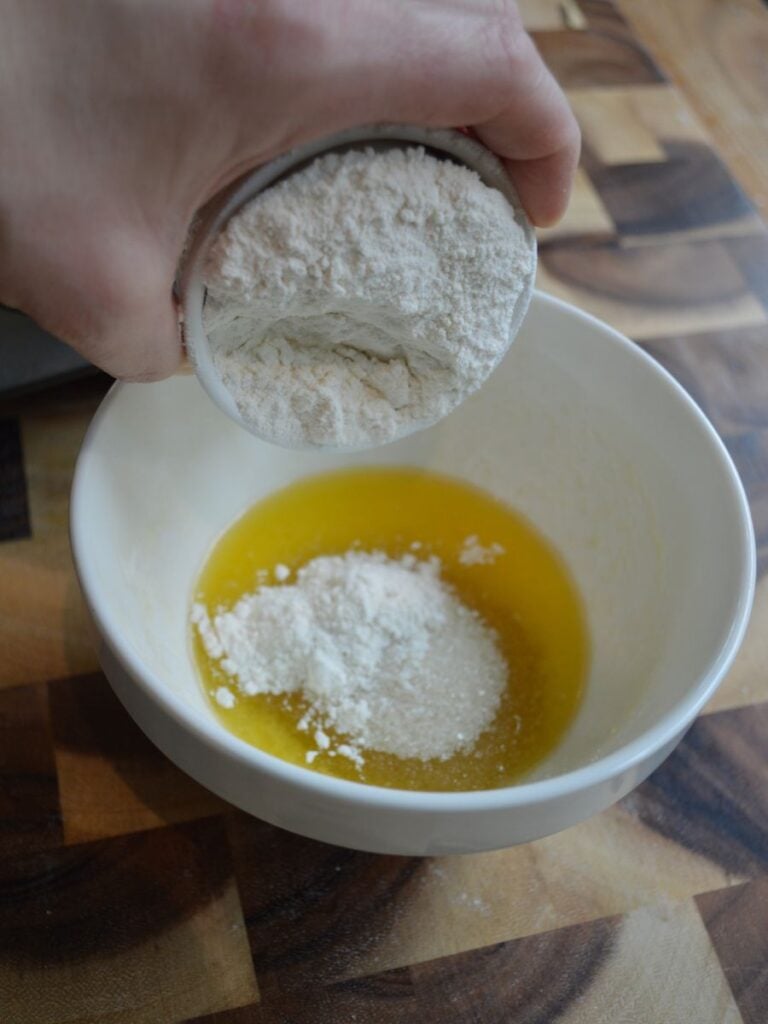 hand adding flour to butter for streusel topping