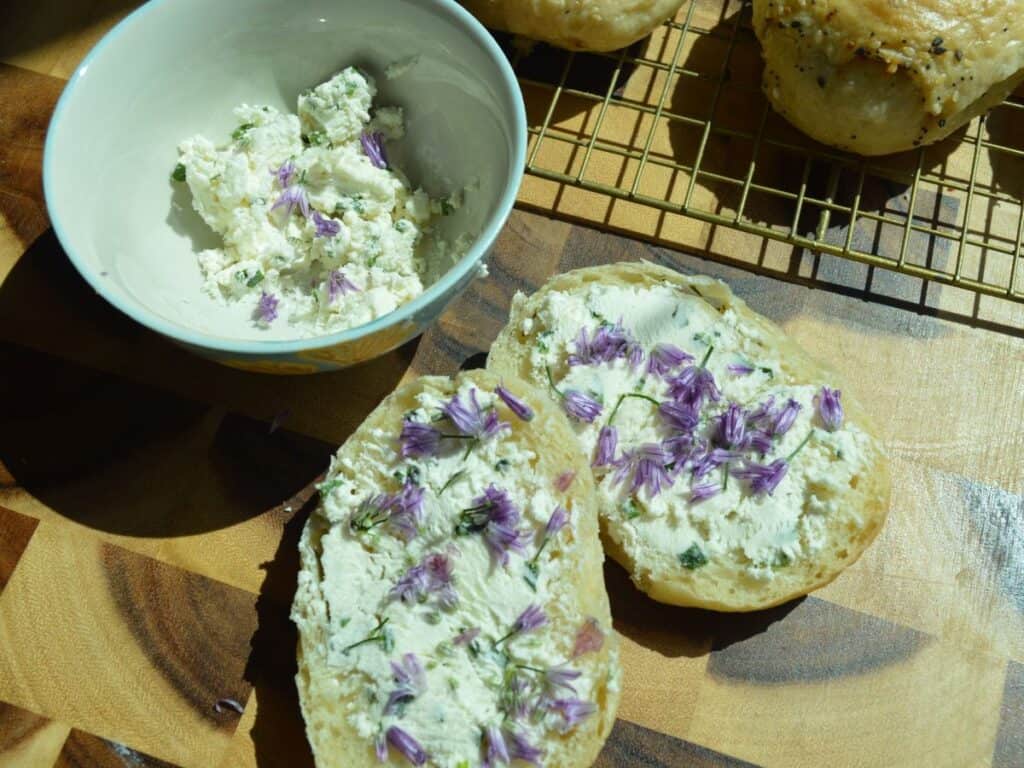Bowl of cream cheese with bagel and chive blossoms